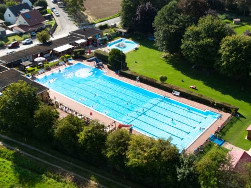 Luftbild vom Freibad mit Schwimmbecken, Kleinkindbecken, Gebäuden und Liegewiese