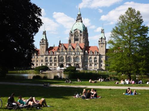 Menschen auf einer Wiese um ein Rathaus.