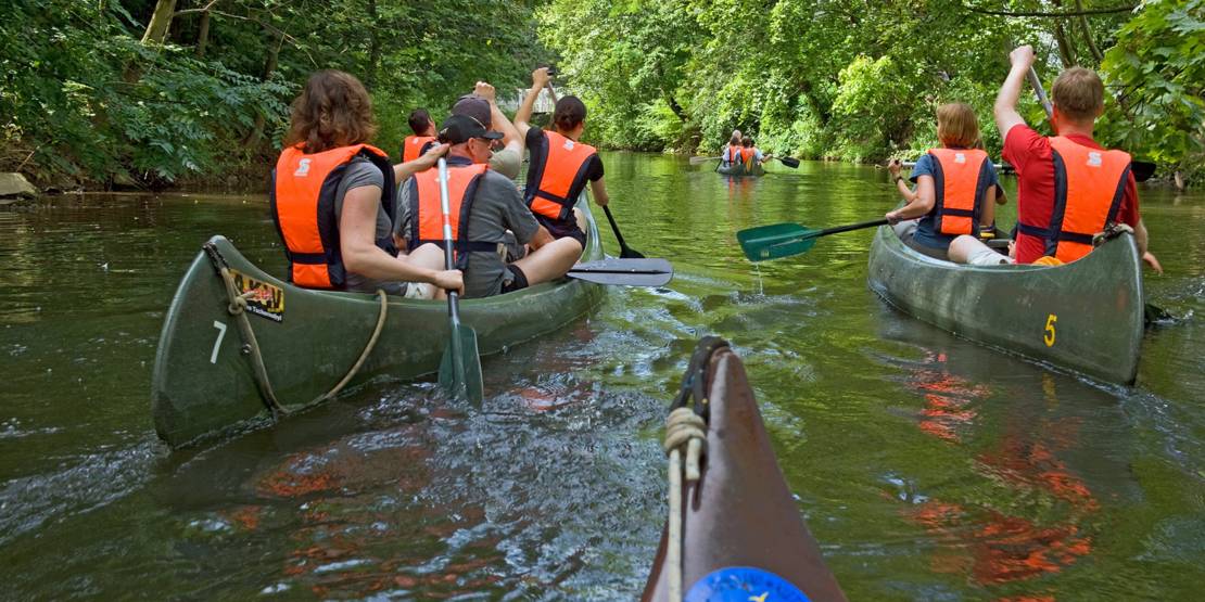 Vier Paddelboote auf einem schmalen Fluß