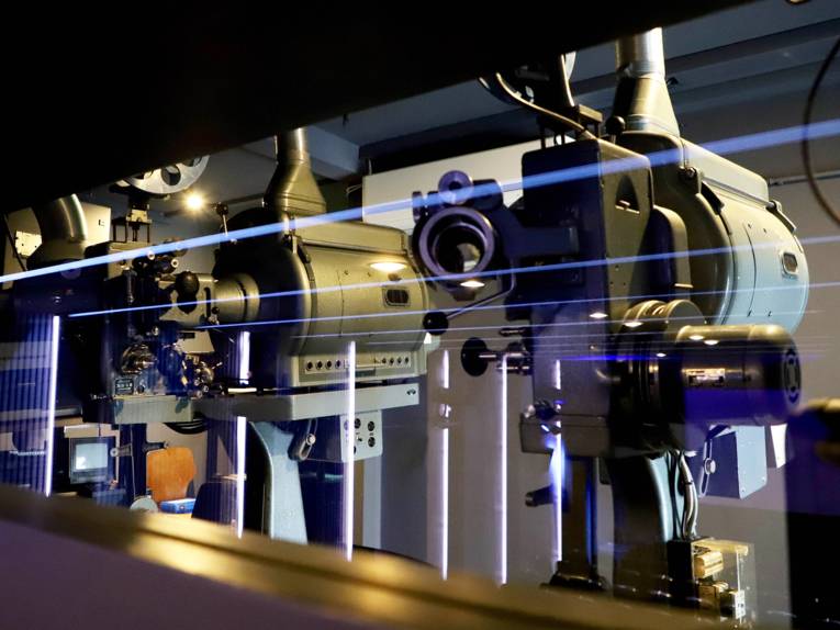 Zu sehen sind die beiden 35mm-Projektoren durch die Scheibe, die den Vorführraum vom Kinosaal trennt