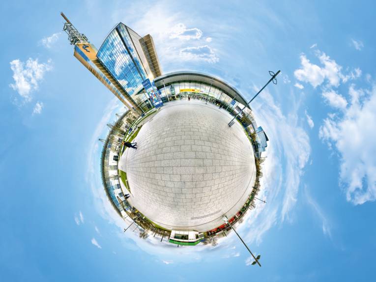 Kreative 360-Grad-Ansicht des Messe- und Kongressgeländes Hannover im „Little Planet“-Stil mit Hochhaus und Eingangsbereich.
